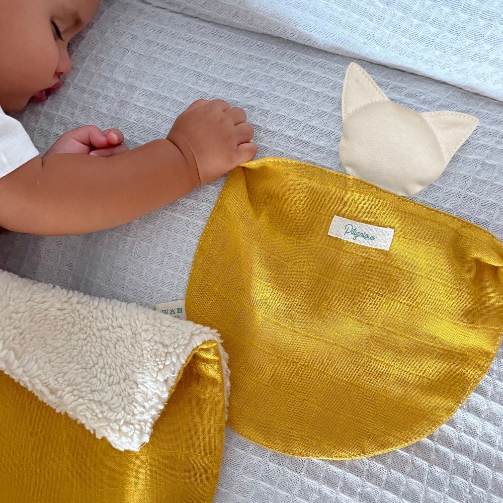 photo d'un bébé qui dort en tenant un doudou plat bio