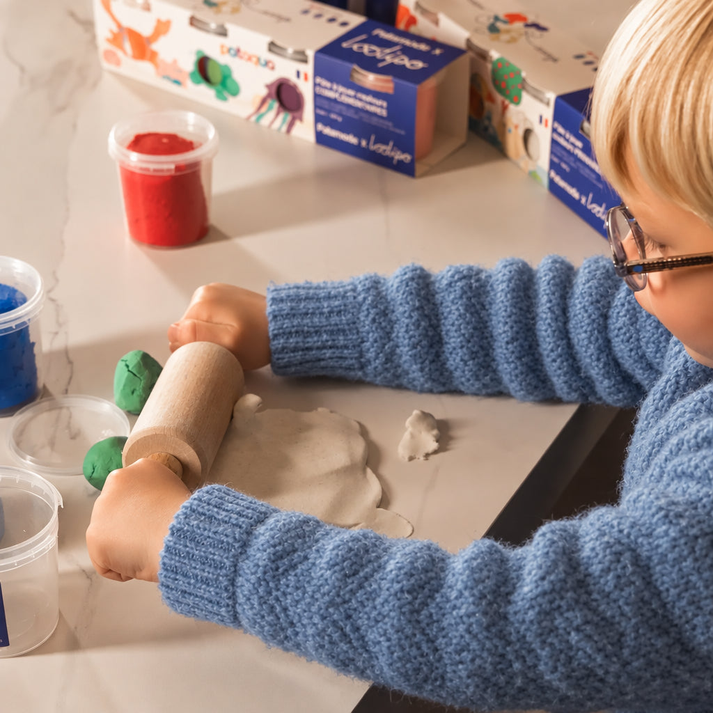 Enfant étalant de la pâte à modeler Made in France au rouleau